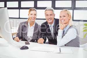 Portrait of smiling business professionals working at computer d