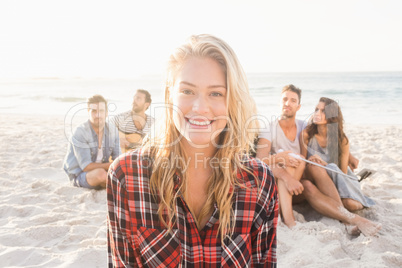 Smiling friends sitting on sand