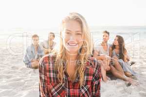 Smiling friends sitting on sand