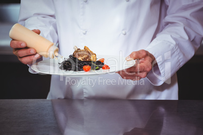 Chef putting sauce on a dish of spaghetti