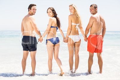 Happy friends holding hands together on the beach