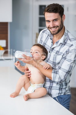 Father feeding milk to son at table