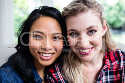 Cheerful beautiful female friends against window