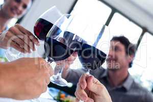 Happy friends toasting wine glass while having lunch