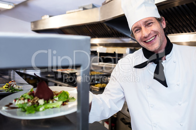 Portrait of a chef handing dinner plate through order station