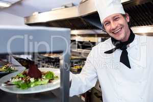 Portrait of a chef handing dinner plate through order station