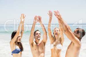 Happy friends raising their hands on the beach