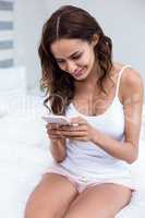 Pretty woman using mobile phone on bed at home