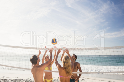 Happy friends playing beach volleyball