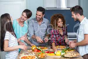 Happy multi-ethnic friends preparing pizza at home