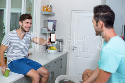 Cheerful man showing phone to friend