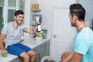 Cheerful man showing phone to friend