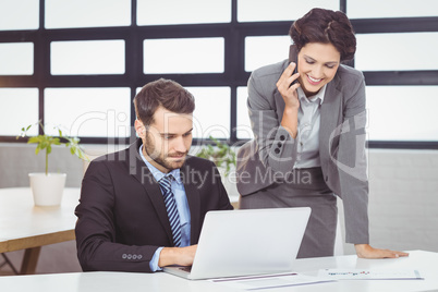 Business people with mobile phone and laptop in office