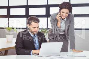 Business people with mobile phone and laptop in office