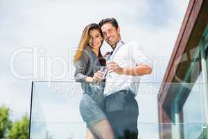 Portrait of happy couple with champagne at balcony