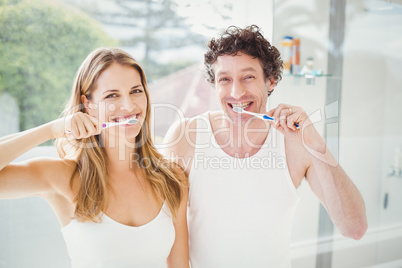Happy couple brushing teeth