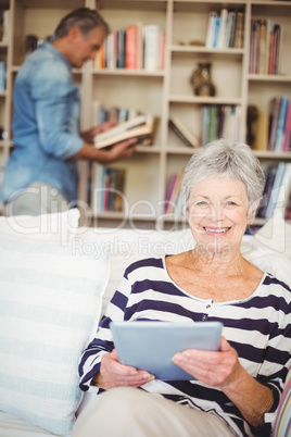 Portrait of senior woman using tablet while sitting on sofa