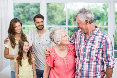 Grandparents embracing while family looking at them