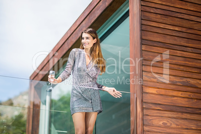 Beautiful young woman standing by glass railing