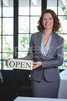 Smiling businesswoman holding open sign