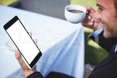 Businessman using tablet and having a coffee