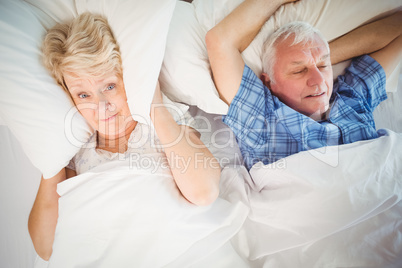 Portrait of woman covering ears from snoring husband