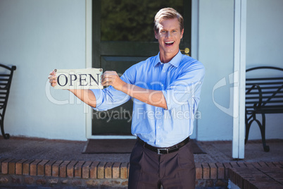 Handsome businessman holding an open sign