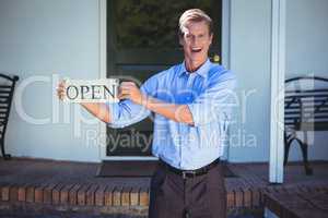 Handsome businessman holding an open sign