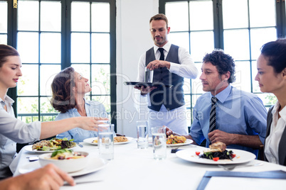 Waiter serving water to business people