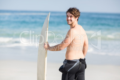 Handsome man holding surfboard on the beach