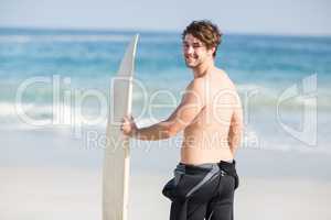 Handsome man holding surfboard on the beach