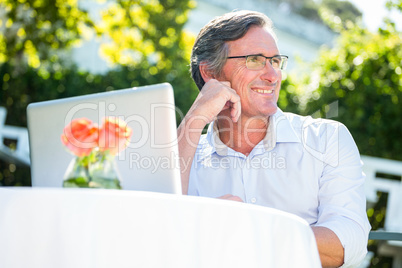 Casual businessman using laptop daydreaming