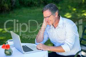 Casual businessman using laptop daydreaming