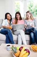 Beautiful female friends looking in laptop at home