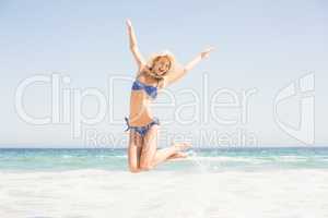 Carefree woman in bikini jumping on the beach