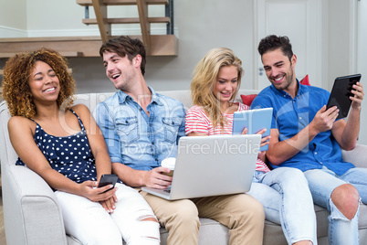 Friends smiling while using technologies at home