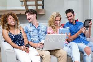 Friends smiling while using technologies at home