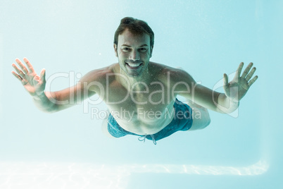 Smiling shirtless man swimming underwater
