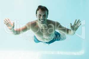 Smiling shirtless man swimming underwater