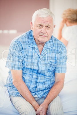 Portrait of tensed senior man sitting on bed