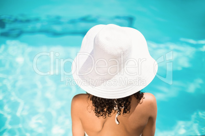 Rear view of woman in white hat sitting near pool