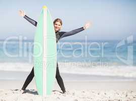 Happy woman in wetsuit with surfboard on the beach