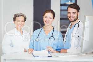 Portrait of smiling doctor team standing at computer desk
