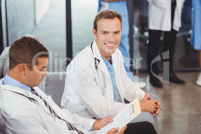 Two doctors with clipboard sitting on sofa