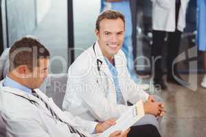 Two doctors with clipboard sitting on sofa