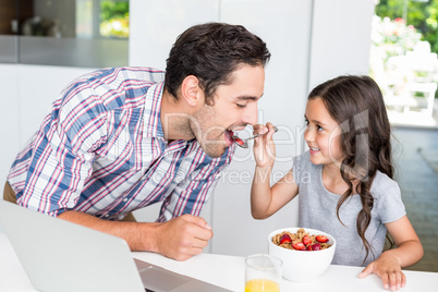 Smiling daughter feeding food to father