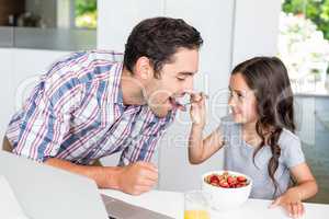Smiling daughter feeding food to father