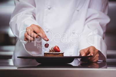 Chef putting a cherry on a dessert