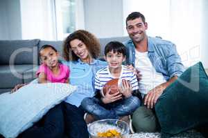 Portrait of family watching american football match on televisio