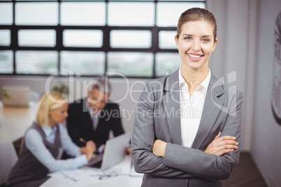 Businesswoman smiling while business people sitting in backgroun